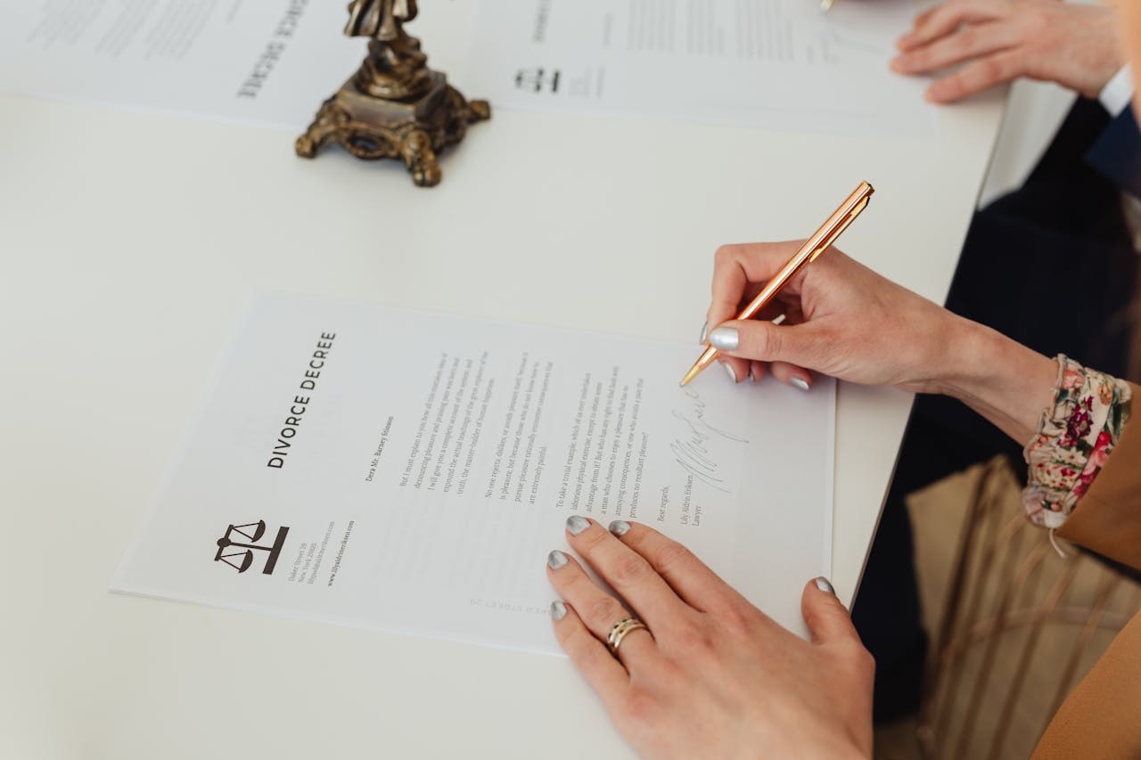 about-us-01 Close-up of hands signing a divorce decree document on a desk, showcasing legal process.